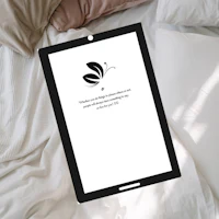 an ipad laying on a bed with a butterfly on it