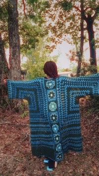 a woman is standing in the woods with her arms outstretched