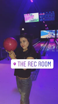 a woman holding a bowling ball in a bowling alley