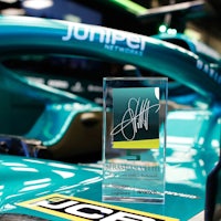 a blue and green racing car with a trophy in front of it
