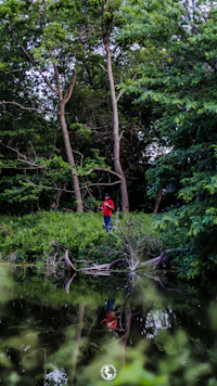 a man in a red jacket standing next to a body of water