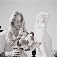 a woman holding a bouquet of flowers in front of a statue
