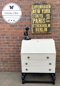 a white and black desk with a sign that says colonial chic