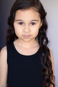 a young girl with long curly hair is posing for a photo