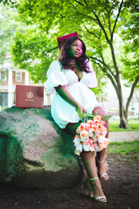 a woman sitting on a rock holding a bouquet of flowers