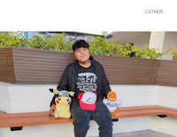 a young man sitting on a bench with stuffed animals