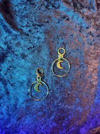 a pair of gold hoop earrings on a blue velvet surface