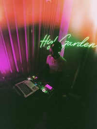 a man is djing in front of a neon sign