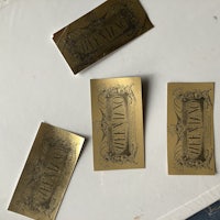 three gold foil stickers on a white surface