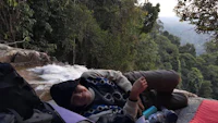 a man laying on a rock next to a waterfall