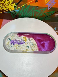 a skateboard with purple paint on top of a white plate