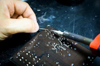 a person is working on a circuit board with a soldering iron