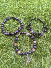 purple and black beaded bracelets laying on grass