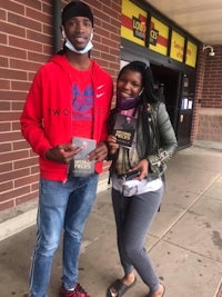 two people standing in front of a store holding books