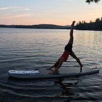 a woman doing yoga on a stand up paddle board