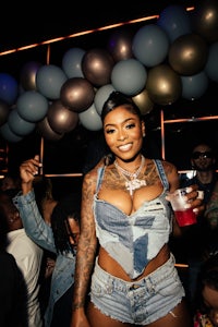 a woman in denim shorts is holding a drink at a party