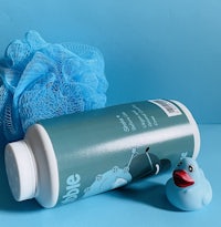 a bottle of blue bubble bath with a rubber duck next to it