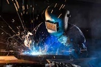 a welder is welding metal in a factory