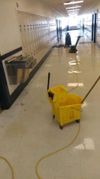 a school hallway with a yellow bucket on the floor