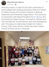 a group of people holding certificates in a hallway