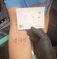 a girl is holding a card with a heart tattoo on it