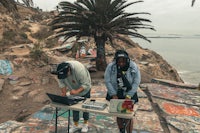 a man and a woman standing on a rock next to a palm tree
