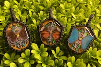 three glass pendants with butterflies on them