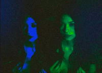 two women standing in front of a blue light