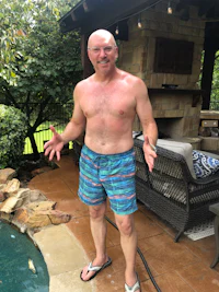 a bald man standing next to a pool