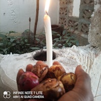 a person holding a candle in front of a pot of food