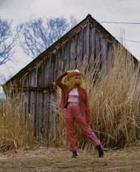 a woman in pink standing in front of a barn