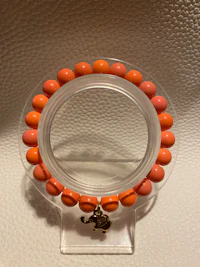 an orange beaded bracelet hanging on a wall