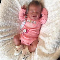 a baby in a pink outfit laying on a blanket