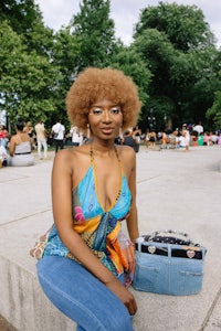 a woman with afro hair sitting on a bench in a park