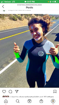 a woman in a wetsuit giving a thumbs up