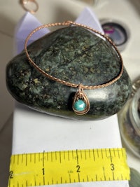 a bracelet with a turquoise stone on top of a rock