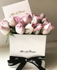 pink roses in a white box with black ribbon