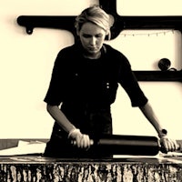 a black and white photo of a woman working with a roller
