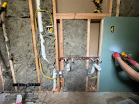 a woman is working on a wall with insulation