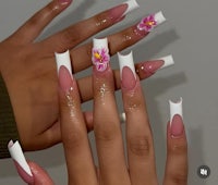 a woman's nails with white and pink flowers on them