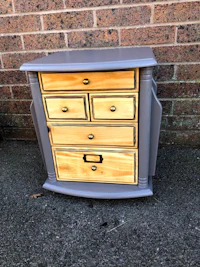 a grey dresser with drawers in front of a brick wall