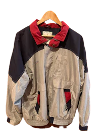 a grey, blue and red jacket hanging on a hanger