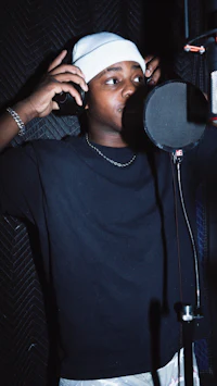 a man wearing a hat and a microphone in a recording studio
