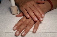 a woman's hands with a white nail polish on them