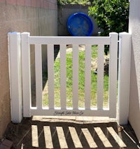 a white gate in a backyard with a blue ball