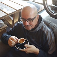 a bald man sitting on a couch with a cup of coffee