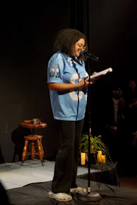 a woman in a blue shirt is standing in front of a microphone