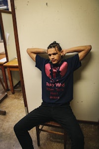 a man sitting on a chair wearing a boxing t - shirt