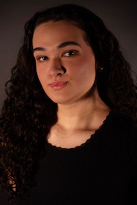 a young woman with curly hair posing for a portrait