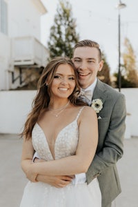 a bride and groom hugging in front of a white building